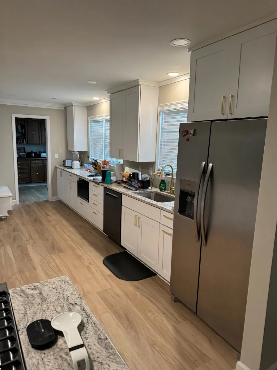 The same kitchen after the remodel: white cabinets and new wood-look flooring