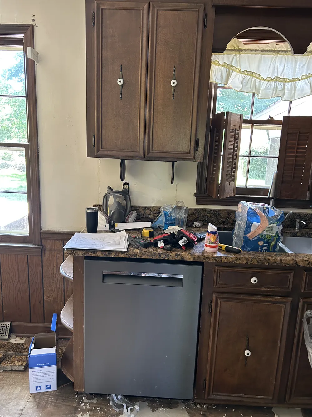 Kitchen before the remodel: dark wood cabinets and cluttered counters